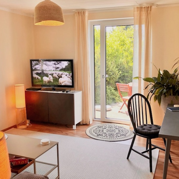 Wohnzimmer mit Homeoffice Space und Blick auf die Süd-Terrasse und ins Grüne