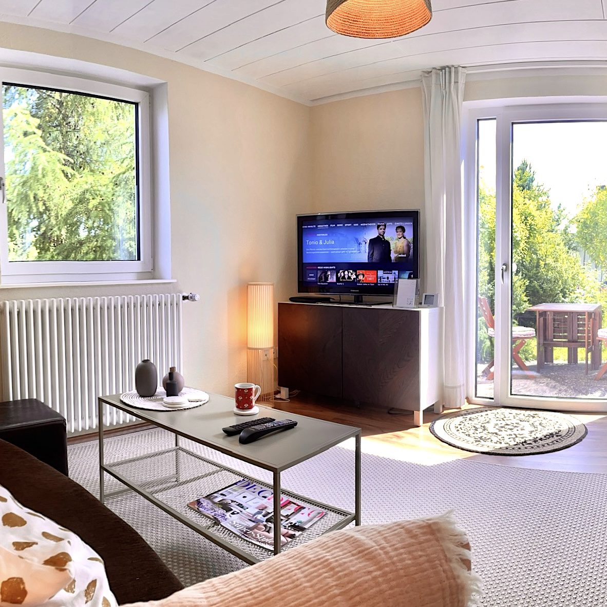 Wohnzimmer mit Homeoffice Space und Blick auf die Süd-Terrasse und ins Grüne